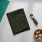 Vintage Charm Green Flower Patch by Judie Rothermel for Marcus Fabrics – folded black cotton fabric with green ditsy florals, styled with rotary cutter, cutting mat, and thread spools