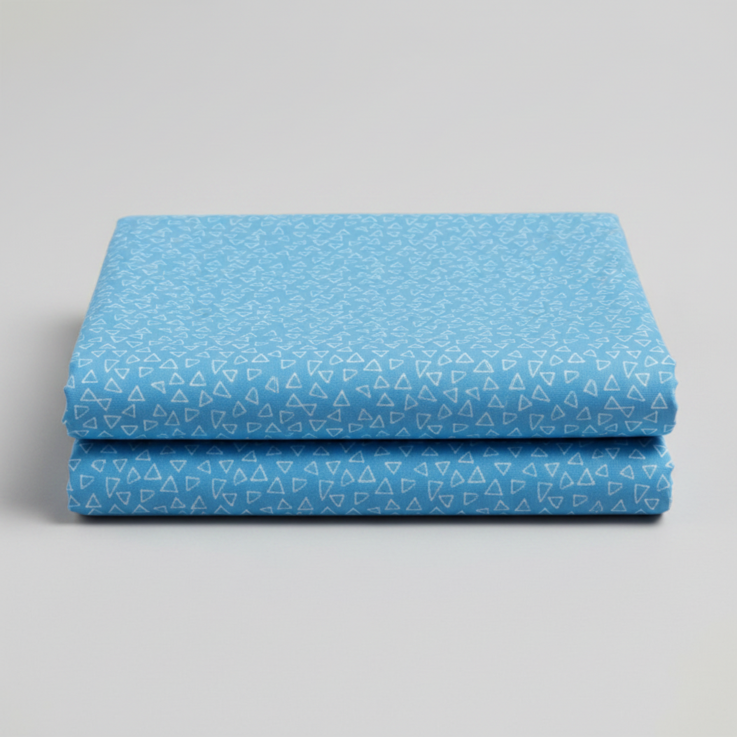 Safari Fun Floating Triangles Blue quilting fabric by Terry Runyan for Benartex – two neatly folded fabric pieces stacked, showing triangle print and fabric weight, light grey background