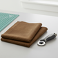 Interwoven Brown by Jason Yenter – quilt room lifestyle shot, fabric partially folded with rotary cutter and cutting mat, light grey base