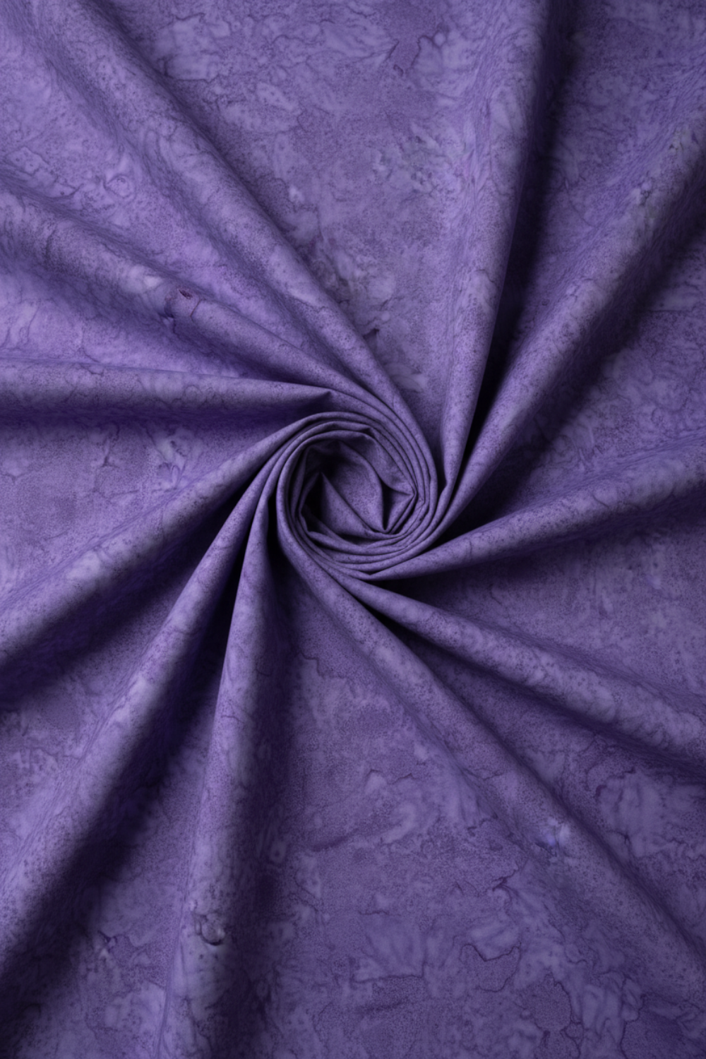 Expressions Batiks Hand-Dyed Purple II – fabric laying flat with hurricane funnel twist fold in the center