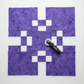 Expressions Batiks Hand-Dyed Purple II – fabric cut in strips and squares for quilt project, rotary cutter visible