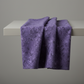 Expressions Batiks Hand-Dyed Dark Purple – fabric draped over edge of table showing deep purple hand-dyed batik texture and drape