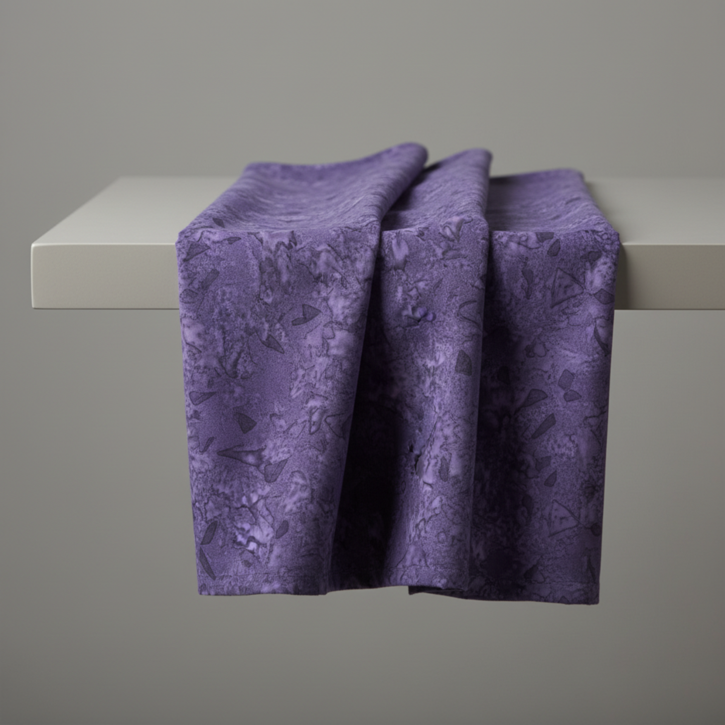 Expressions Batiks Hand-Dyed Dark Purple – fabric draped over edge of table showing deep purple hand-dyed batik texture and drape