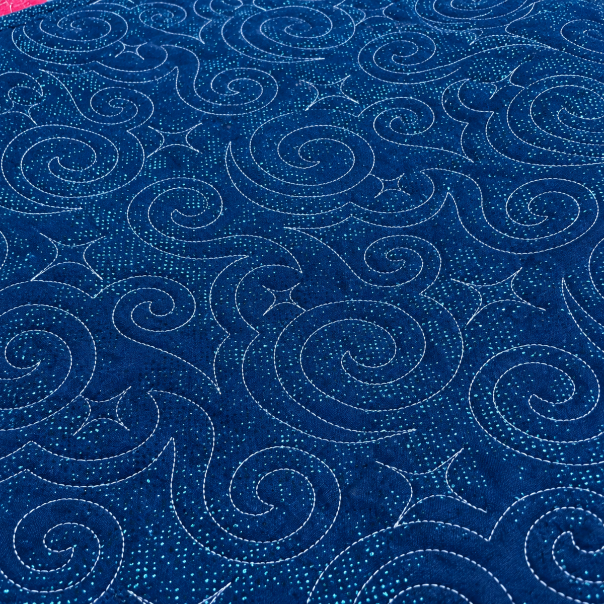 Dark blue backing of Starry Night quilt with scattered aqua speckles and flowing spiral stitching.