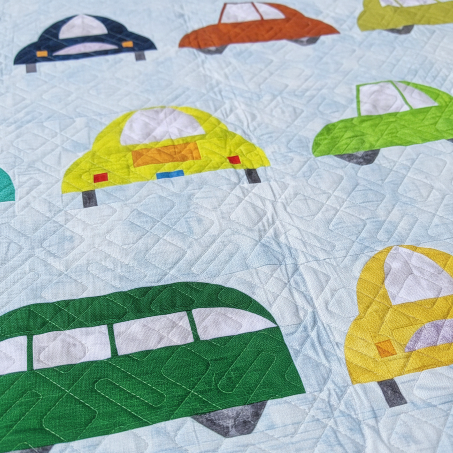 Close-up of colorful car blocks and geometric quilting on Cool Cars quilt