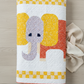 Playful handmade elephant baby quilt in soft yellow, gray, and orange tones