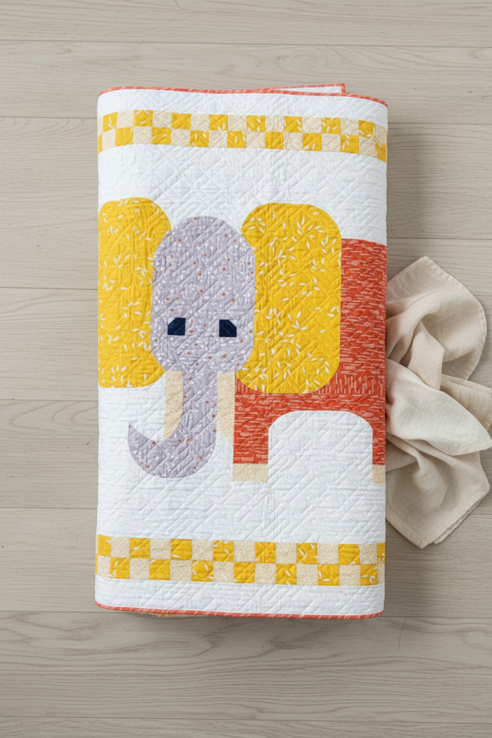 Playful handmade elephant baby quilt in soft yellow, gray, and orange tones