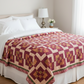 Bed with a red and beige quilt in a bedroom setting