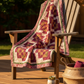 Quilt draped over a wooden chair on a wooden deck with a blurred natural background