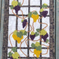 Grapevine quilted wall hanging with purple and golden grapes, green leaves, and black trellis border on a clean light background.