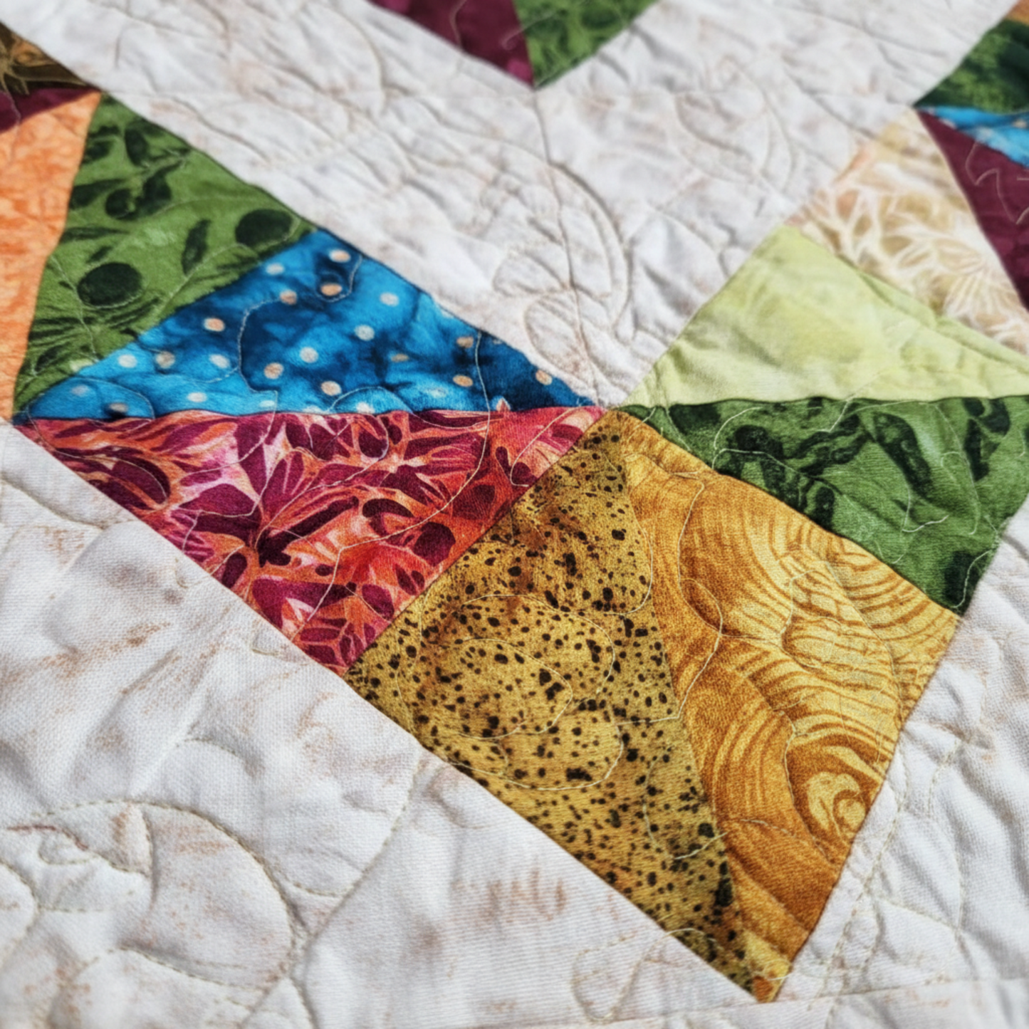 Close-up of 4‑Patch Charm quilt showing vibrant batik four‑patch blocks, textured quilting, and a corner folded to reveal coordinating backing.