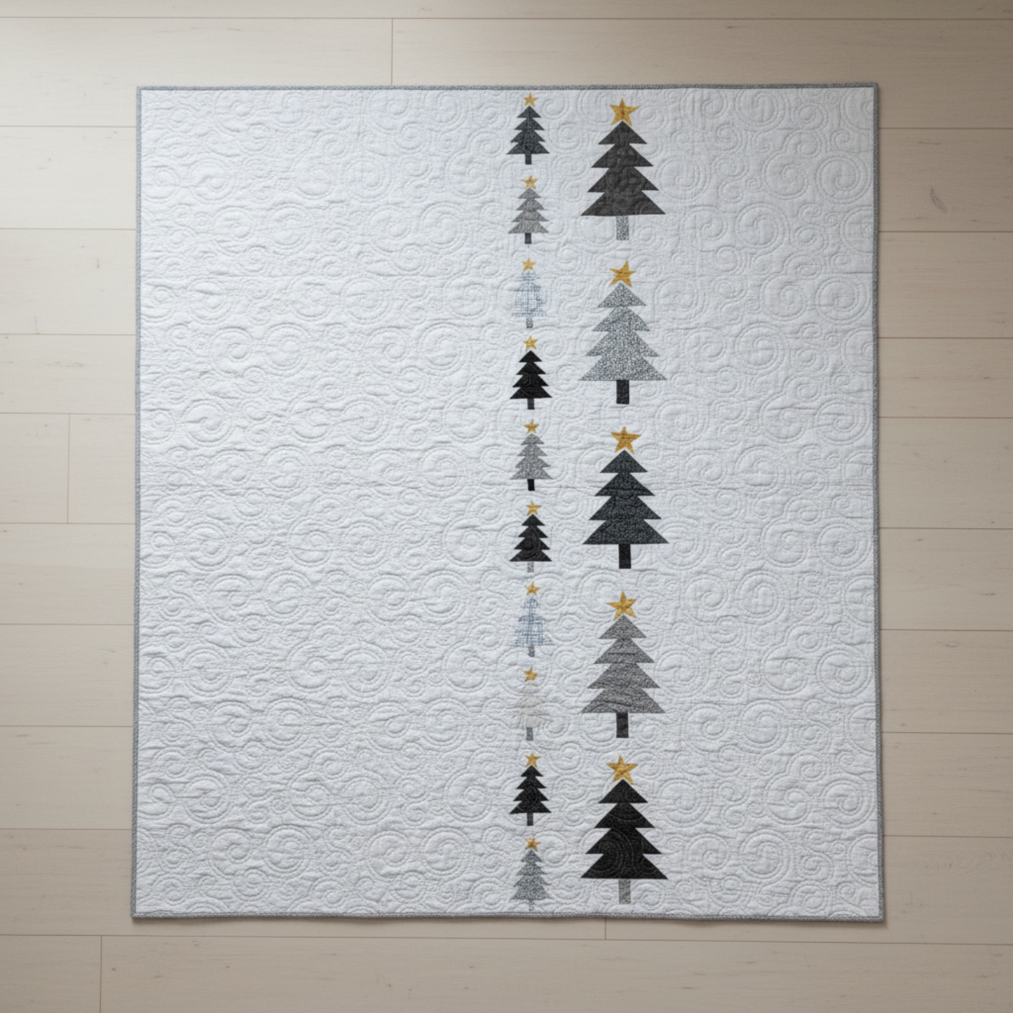 Modern handmade winter quilt with gray and black tree motifs and gold stars on a white background, 56 x 67 inches