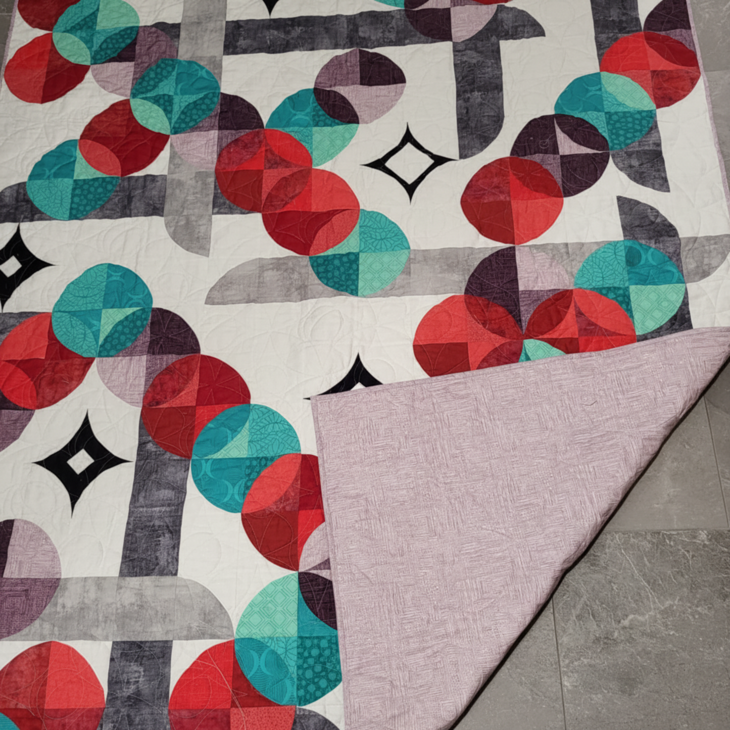 Moon Dance quilt showing modern circular design and soft coordinating backing