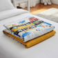 Folded On the Go quilt showing playful transportation print front and mustard yellow backing with colorful stripe binding.