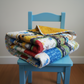 Colorful quilt folded on a blue chair against a plain background