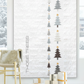 Decorative wall art with Christmas tree designs and presents on a white brick wall.