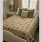 Scrappy patchwork quilt on a bed featuring small repeated blocks in a vintage color palette