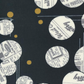 Celestial News Dropping Onyx by Zen Chic for Moda Fabrics — close-up of the bold graphic print showing large cream vintage newspaper circles and gold metallic dots on black cotton. 43"/44" wide. Perfect for modern quilts, sashing, and statement blocks!