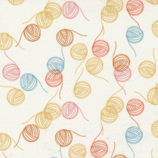 Close-up of Lazy Afternoon Vanilla Multi fabric by Zen Chic for Moda Fabrics, showing scattered pastel yarn balls and loose strands on vanilla.