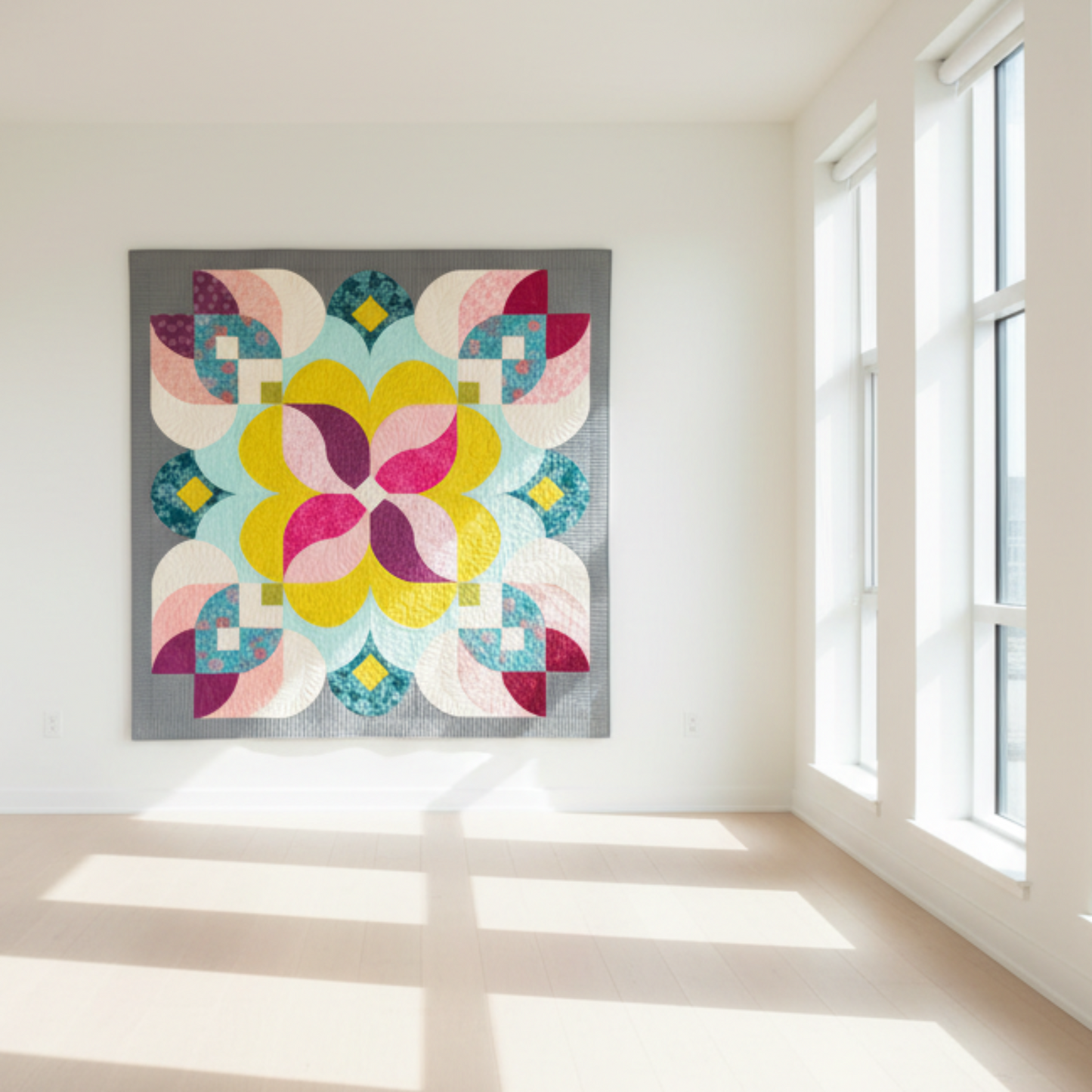 Colorful geometric quilt hanging on a white wall in a bright room with large windows.