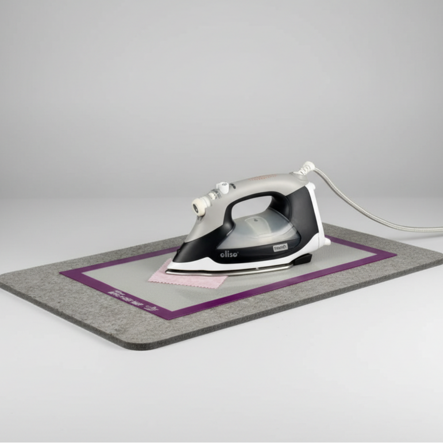 Silicone Appli-Fuse Mat placed on a wool pressing mat with iron and fabric, protecting work surface during fusing.