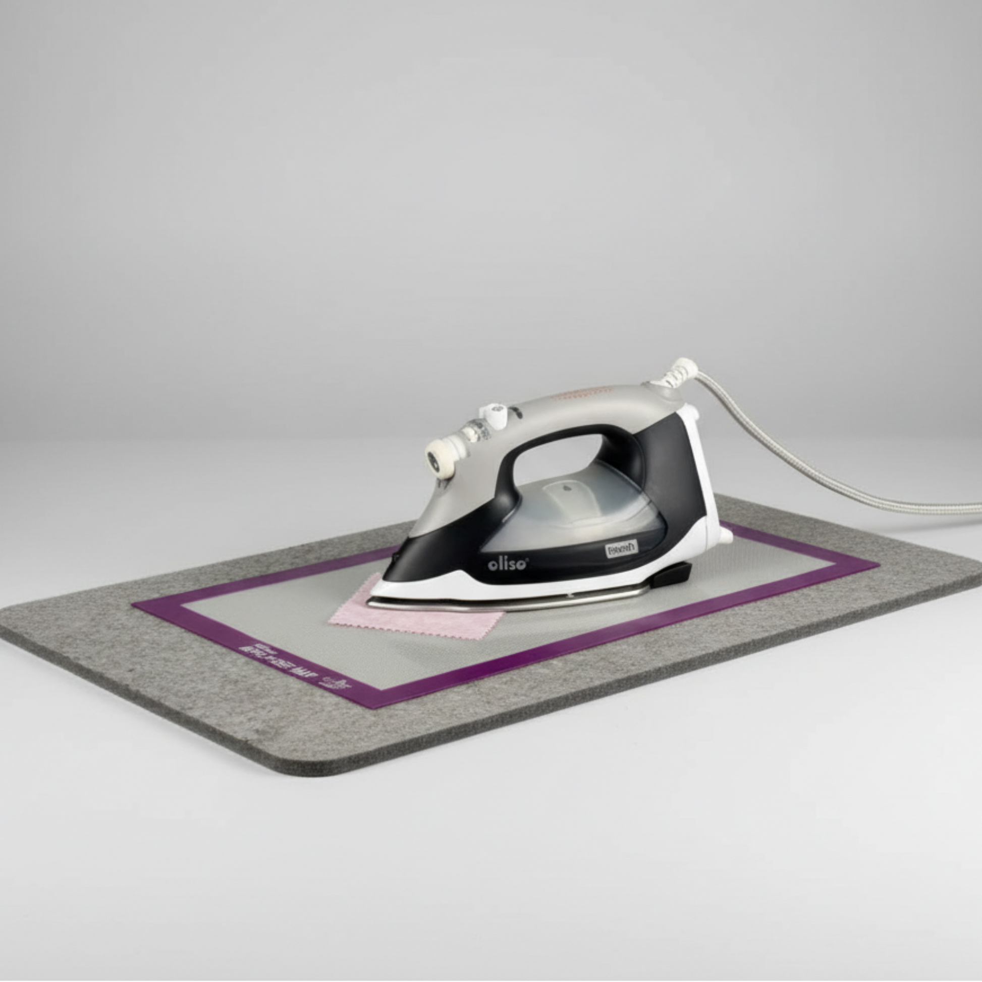Silicone Appli-Fuse Mat placed on a wool pressing mat with iron and fabric, protecting work surface during fusing.