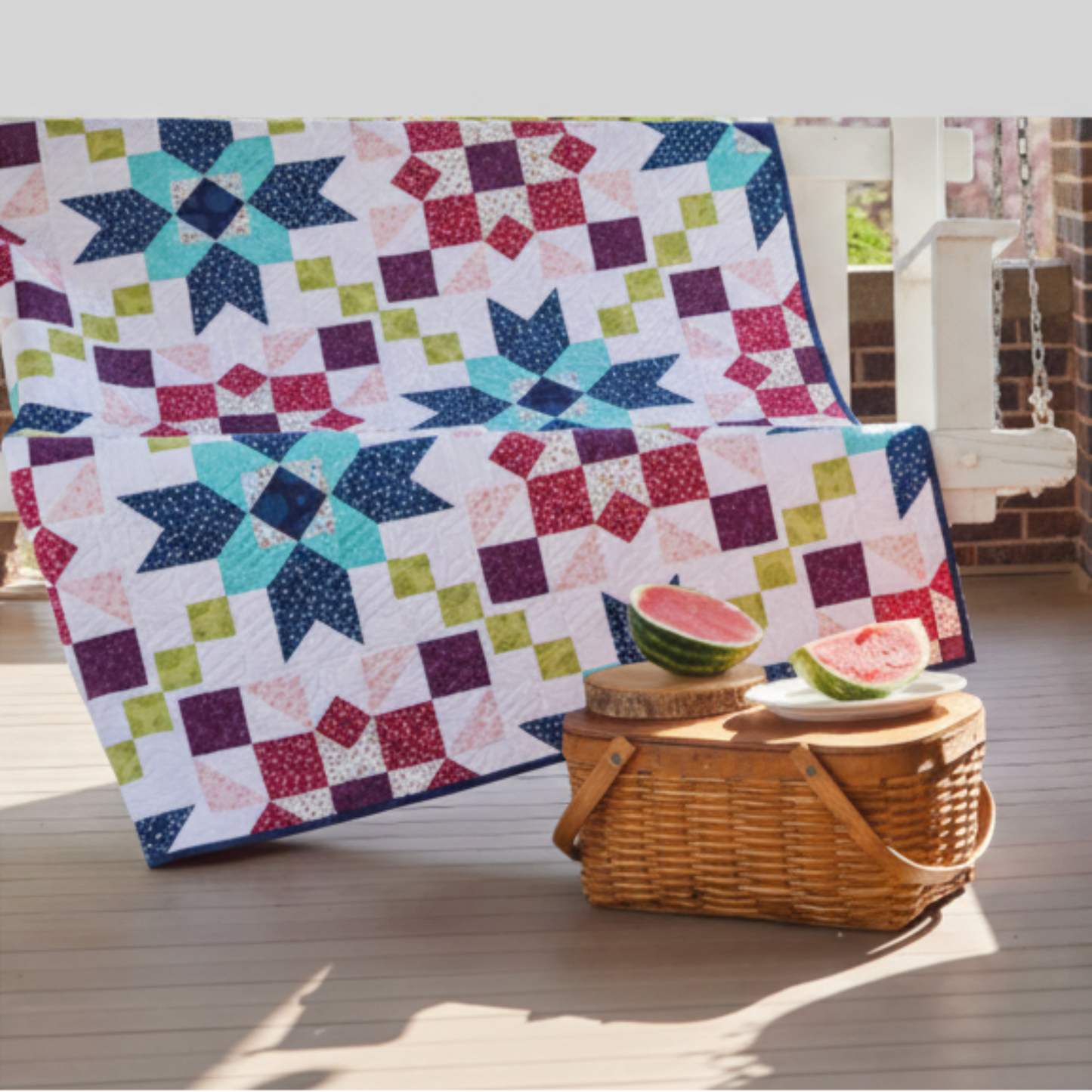 Barn star sampler quilt – star quilt displayed on porch with picnic basket and watermelon