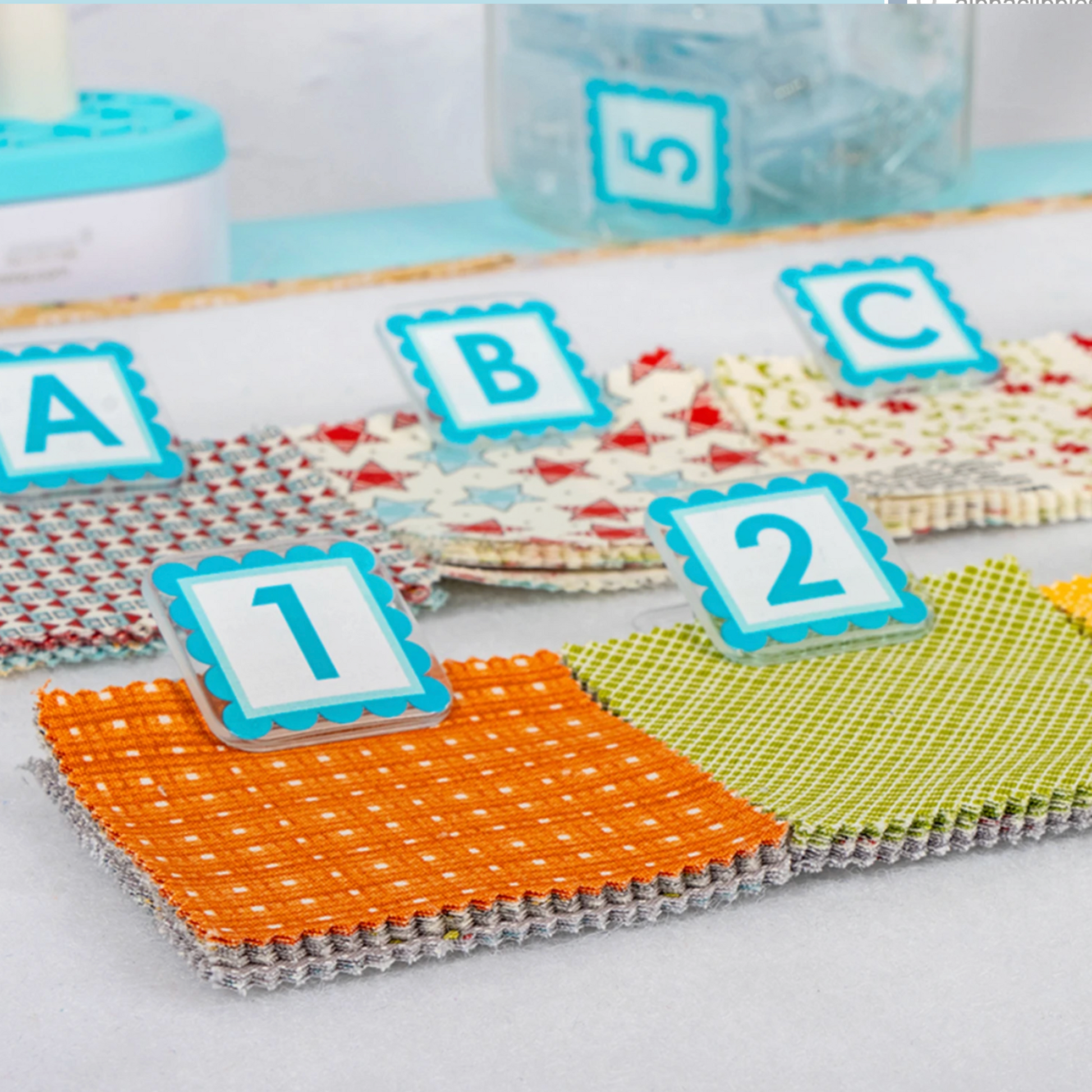 Close-up of AlphaClippies specialty marking clips labeling colorful quilting fabric squares with letters and numbers