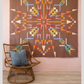 Northern Lights quilt displayed on blush pink wall with colorful modern geometric design and wicker accent chair