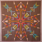 Close-up of Northern Lights quilt featuring vibrant geometric starburst pattern in pink, orange, teal, yellow, and brown fabrics