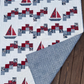 Handmade Sailing School sailboat quilt displayed on a wooden deck with one corner folded back to show the blue patterned backing.
