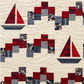 Close-up of handmade sailboat quilt showing red and navy sailboats, patchwork blocks, and wave quilting texture.