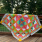 Colorful handmade In the Jungle quilt displayed outdoors, featuring tropical animals, bright patchwork blocks, and detailed quilting.