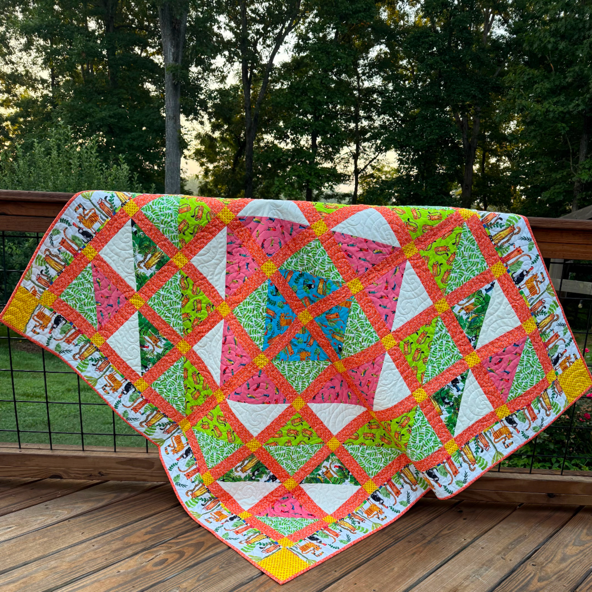 Colorful handmade In the Jungle quilt displayed outdoors, featuring tropical animals, bright patchwork blocks, and detailed quilting.
