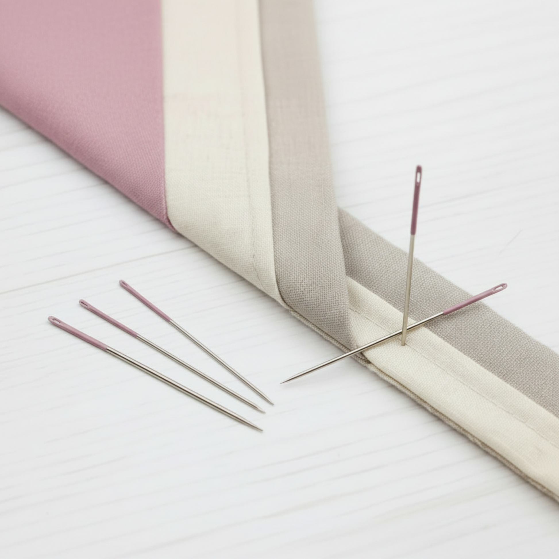 Lori Holt binding needles with pink eyes used for hand-stitched quilt binding on folded fabric