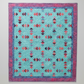 Colorful quilt with geometric pattern on a light gray background