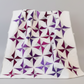 Quilt with purple and white geometric pattern on a gray background