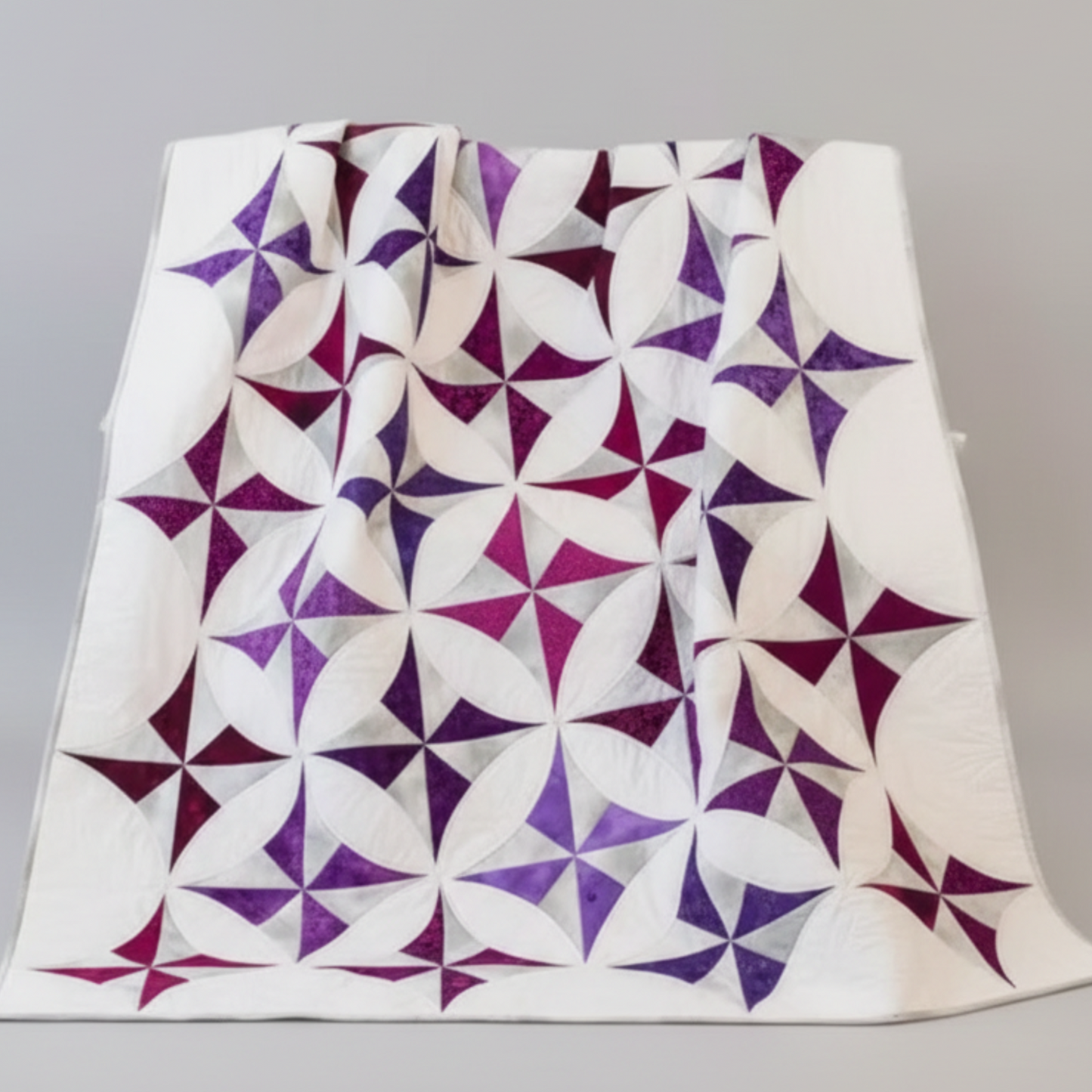 Quilt with purple and white geometric pattern on a gray background