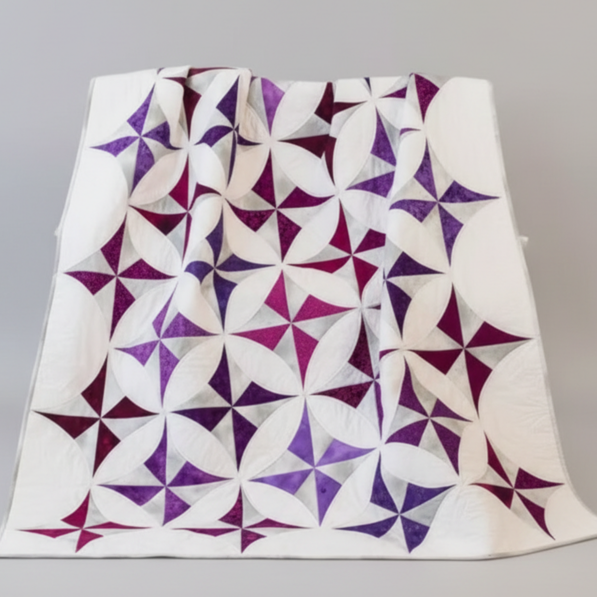 Quilt with purple and white geometric pattern on a gray background