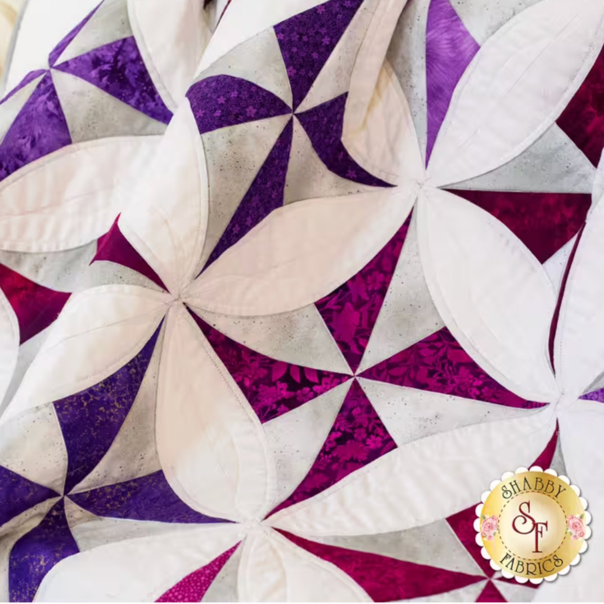 Quilt block with purple and white triangles, Shabby Fabrics logo visible