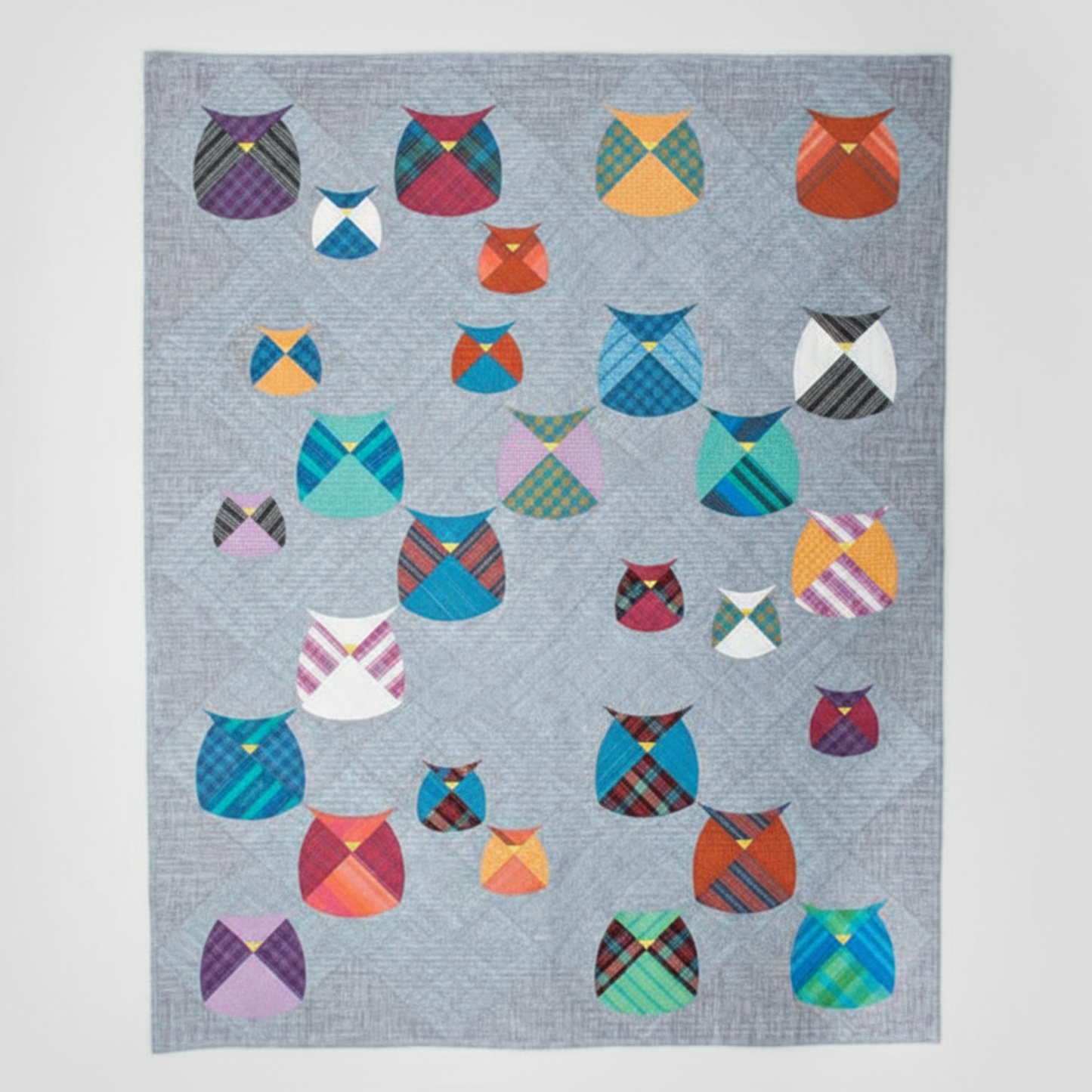 Quilt with colorful owl patterns on a gray background