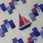 Quilt with sailboat pattern in blue and red on a white background