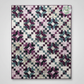 Quilt with star pattern in purple, black, and white on a white background