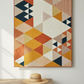 Colorful geometric quilt hanging on a wall above a wooden table with a hat.