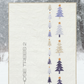 Framed artwork with vertical Christmas tree illustrations and 'Those Trees 2' text against a snowy forest background.