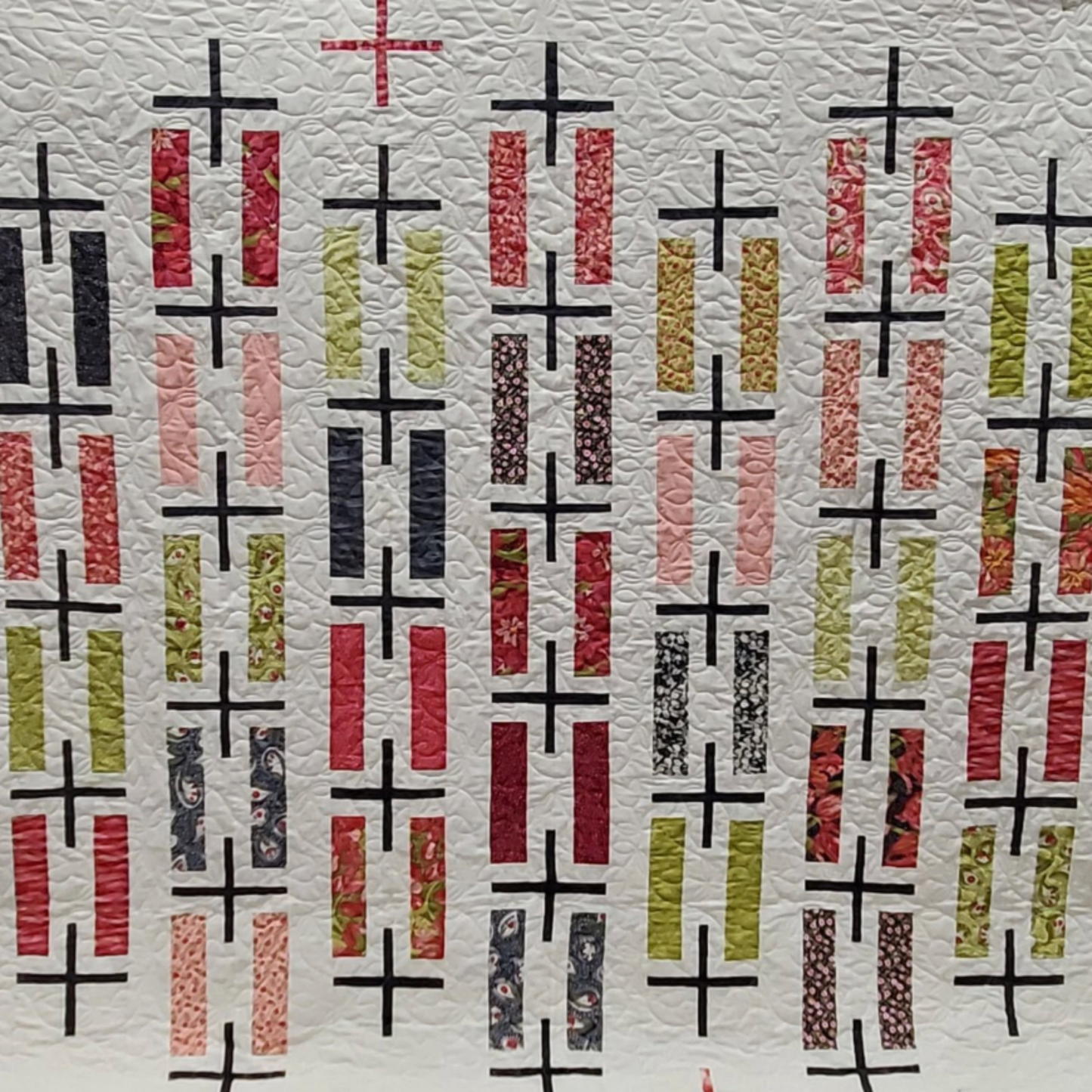 Quilt with geometric pattern featuring black plus signs and colorful bars on a textured background