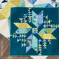 Quilt with geometric pattern on a wooden surface, featuring blue and yellow colors.