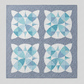 Quilt with blue and white geometric pattern on a gray background