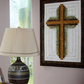 Decorative cross artwork on a wall next to a lamp with a white shade.