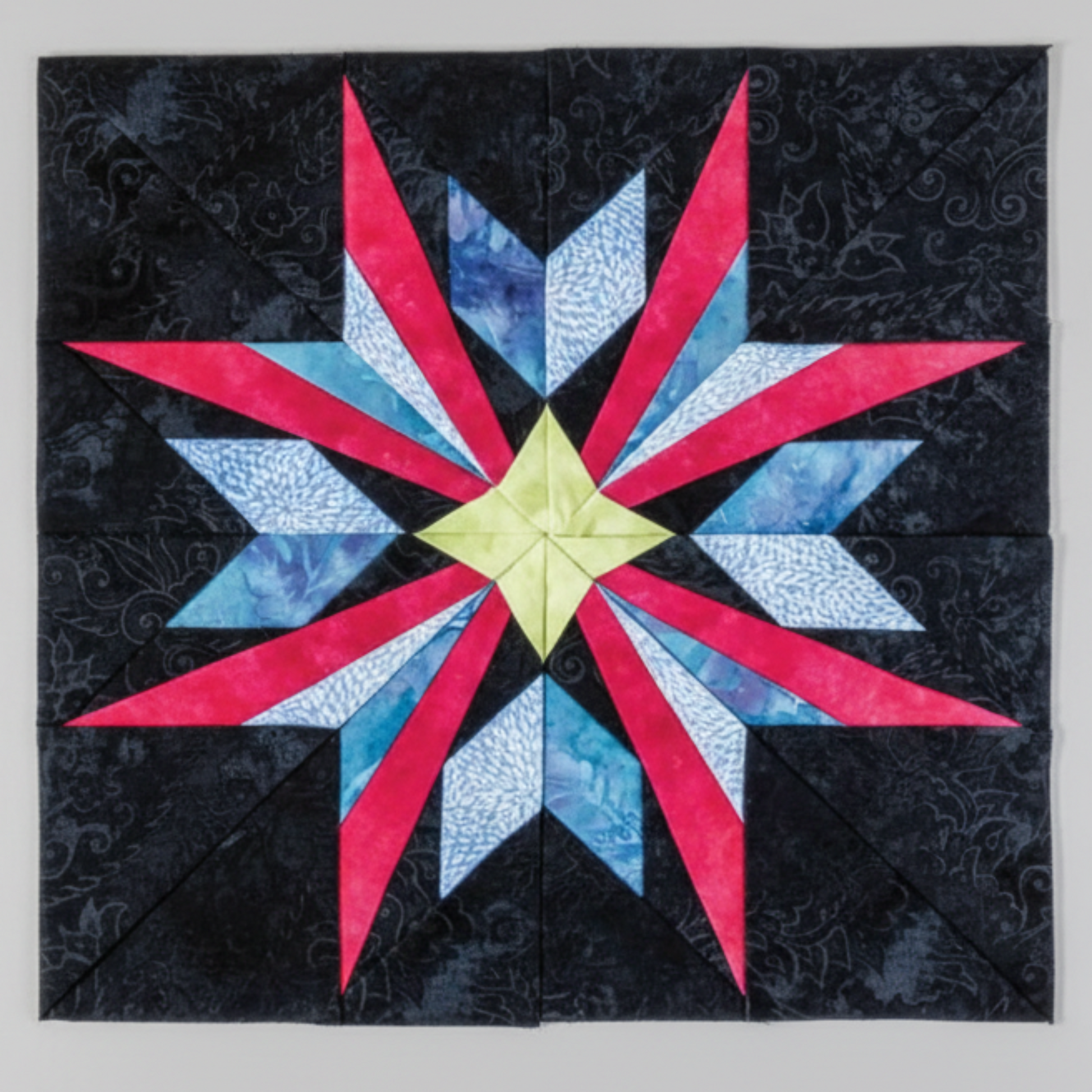 “Paper-pieced star quilt block in red, blue, and yellow fabrics from 60 Fabulous Paper-Pieced Stars book”